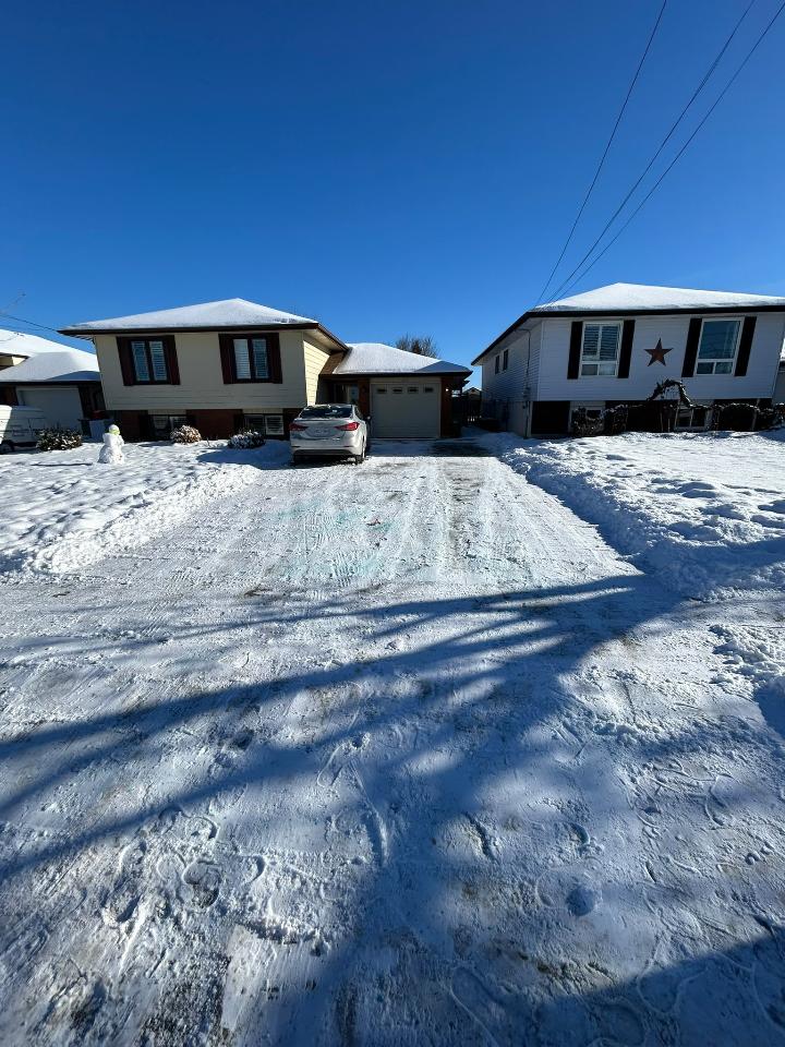 Cleared residential driveway between two Peterborough homes on a sunny winter morning