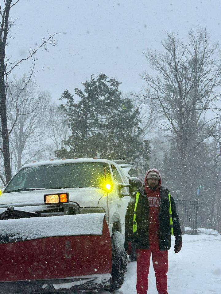 SnowBROS operator standing beside plow truck during heavy Peterborough snowstorm